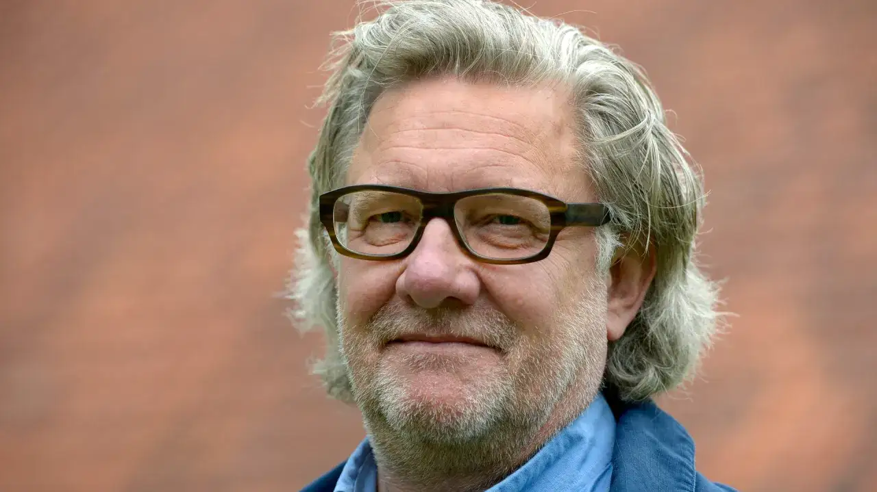 Johan Croneman, med sitt gråa hår och glasögon, ler mot kameran.