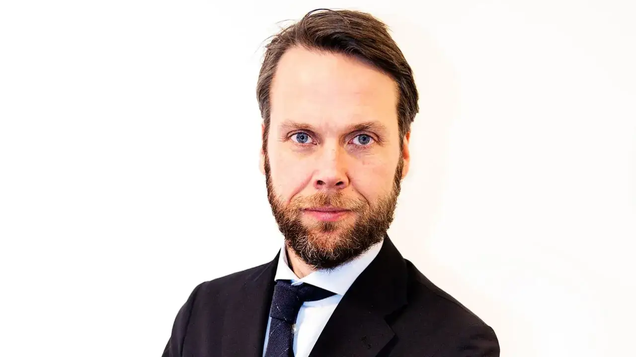 Portr&auml;tt av Magnus Alselind, en man med sk&auml;gg och bl&aring; &ouml;gon, kl&auml;dd i kostym och slips.