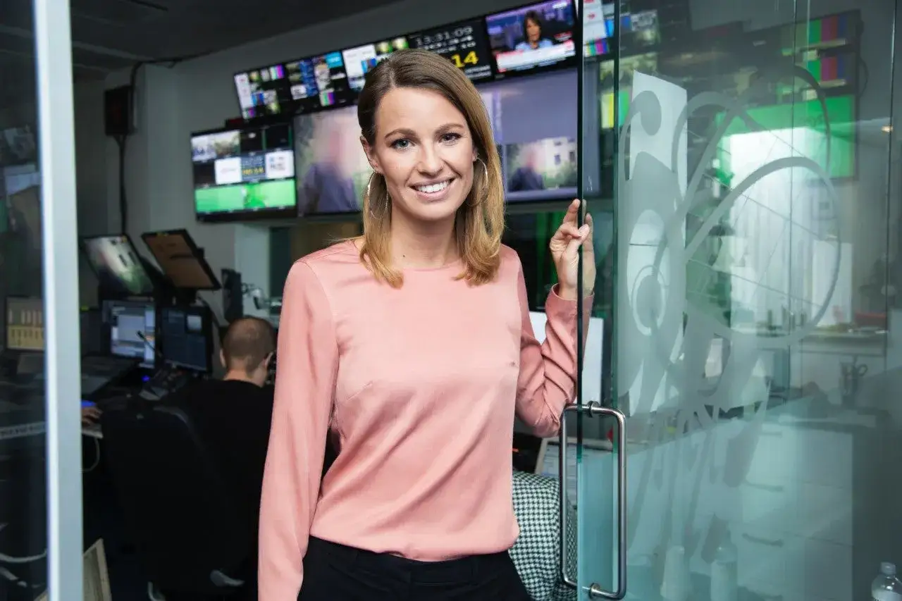 Jennie Pierrou ler vid en glasd&ouml;rr i en kontrollrumsmilj&ouml; med m&aring;nga sk&auml;rmar.