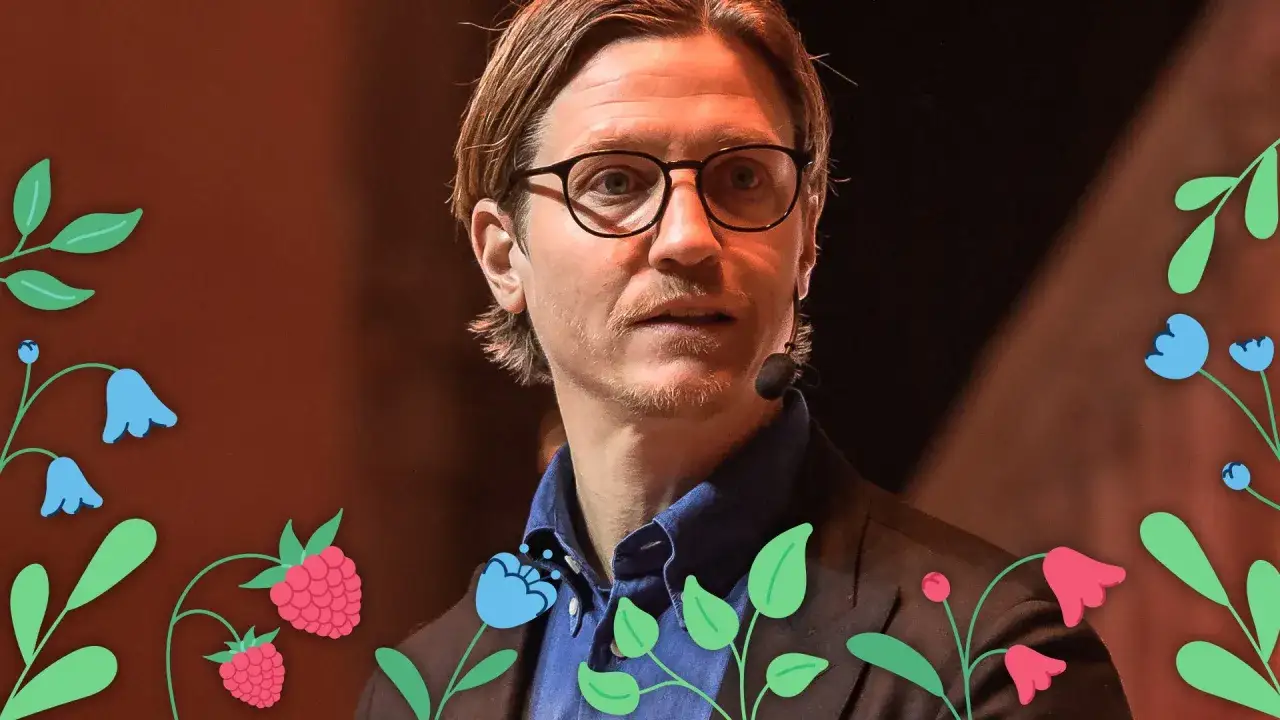Alexander Lydecker med glasögon och blå skjorta, omgiven av blommor och hallon.