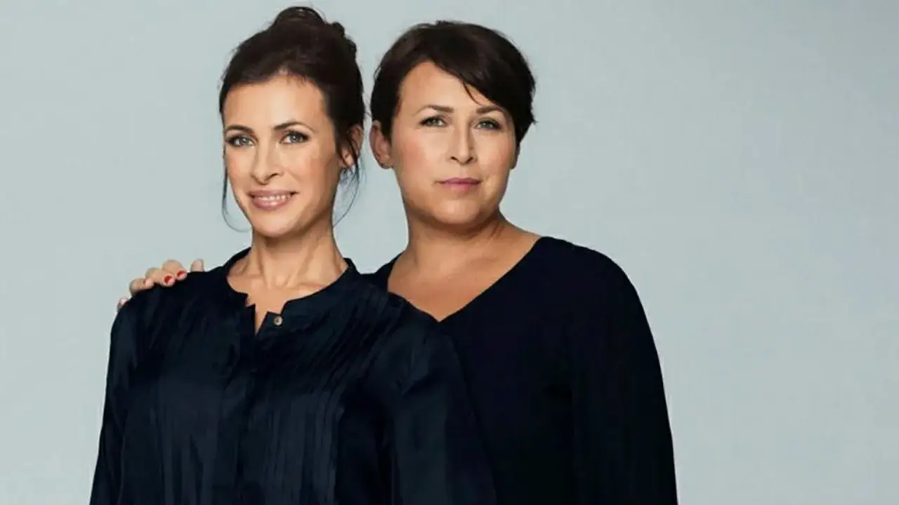 Hannah och Amanda, två kvinnor i mörka toppar, poserar tillsammans.