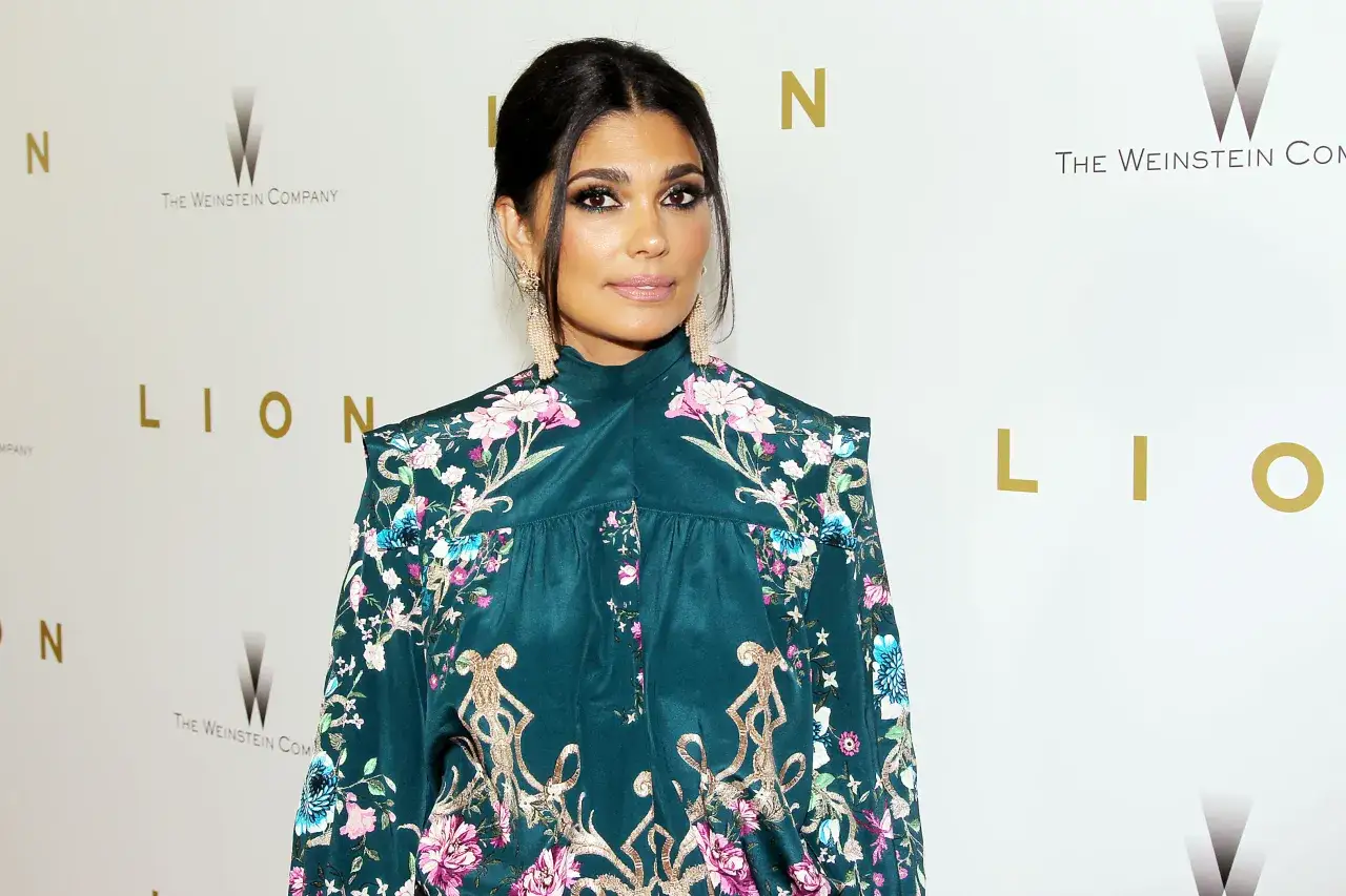 Rachel Roy i en mörkgrön klänning med blomstermönster och stora örhängen.