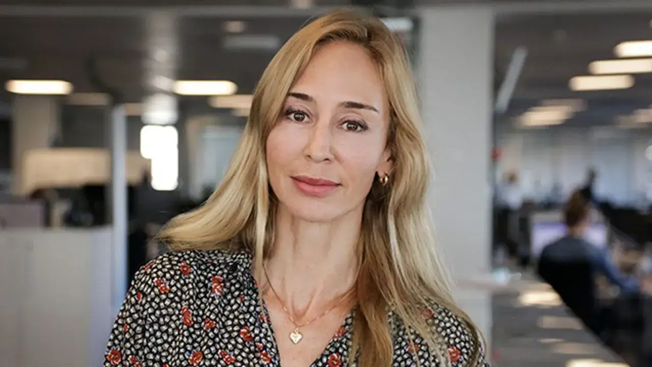 Karin Ekman från SVT, med sitt blonda hår och blommiga klänning, ser rakt in i kameran.