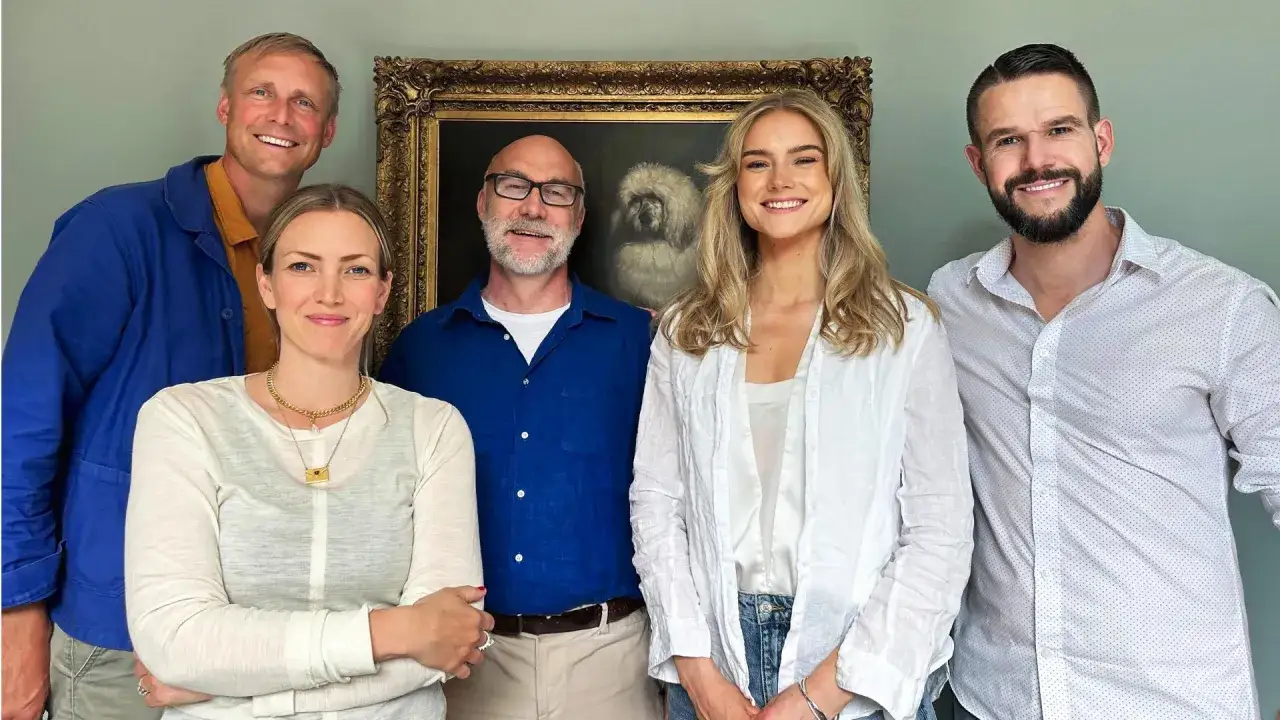 Johnny Kroneld och hans familj poserar glatt framför en hundporträtt.