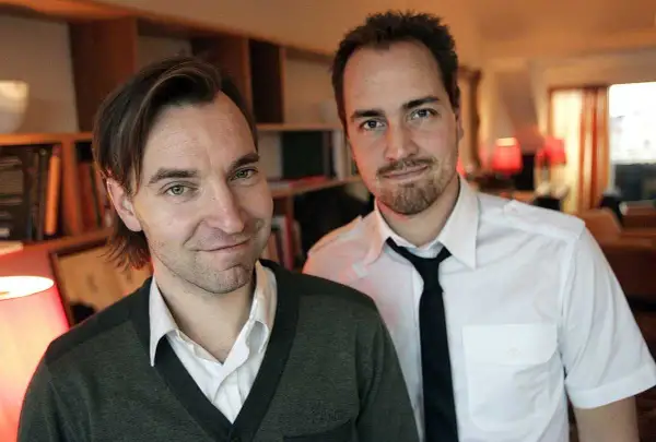 Två män, varav en är Måns Mårlind, poserar framför bokhyllor.