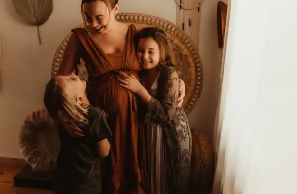 Laura, the Swedish family, väntar sitt tredje barn. Barnen kramar mammans mage med kärlek.