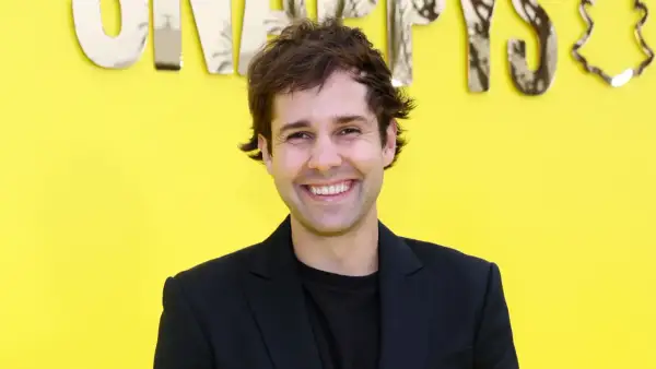 David Dobrik ler framför en gul bakgrund med texten "Snapchat". Kanske han vet hur man får alla trofeer på Snap?