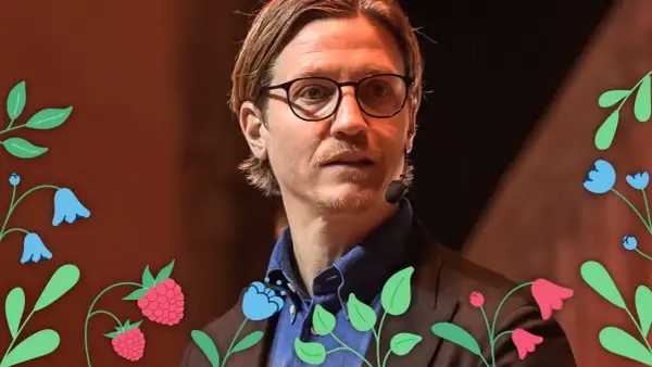 Alexander Lydecker med glasögon och blå skjorta, omgiven av blommor och hallon.