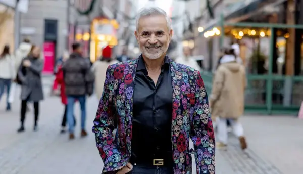 Panos Papadopoulos, en man med grått hår och skägg, ler i en färgglad kavaj med dödskallemönster.