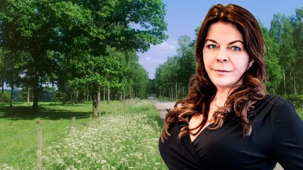 Jennifer Wegerup i en vacker sommarmiljö med en väg kantad av träd och blommor.