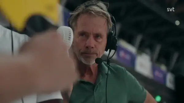 En svt sport medarbetare med headset och mikrofon, redo att rapportera från en sportarena.