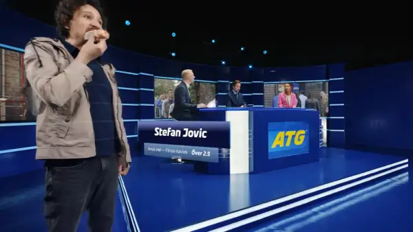 Man äter korv i en studio med ATG-reklam.